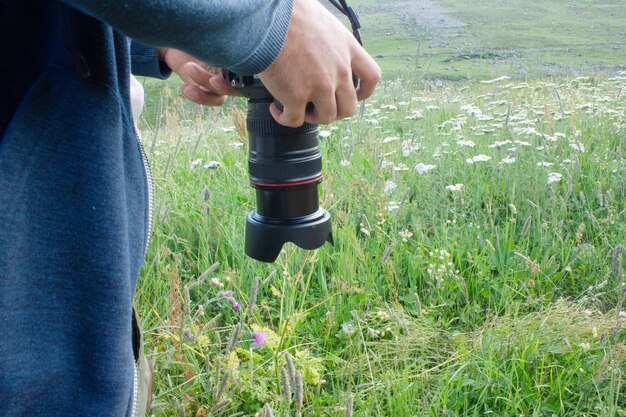 カメラマンは山の花の写真を撮ります
