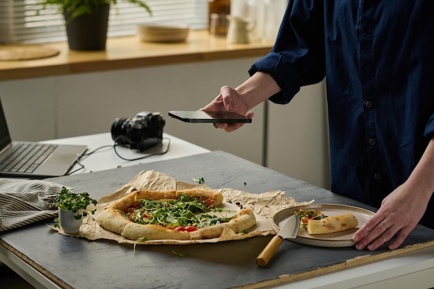 Photographer taking photo of pizza on the phone