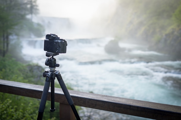 Фотограф, делающий фотографию водопада рано утром