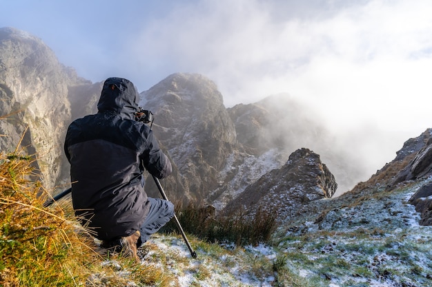 A photographer taking a photo with the tripod in the snowy winter sunset, on the mountain of Peñas de Aya in the town of Oiartzun near San Sebastian, Spain