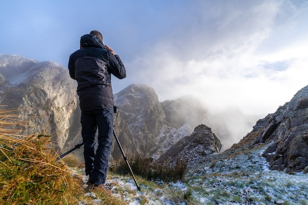 A photographer taking a photo with the tripod in the snowy winter sunset, on the mountain of Peñas de Aya in the town of Oiartzun near San Sebastian, Spain