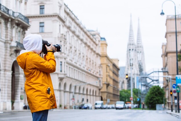 photographer tourist taking picture of city street with votive church on background