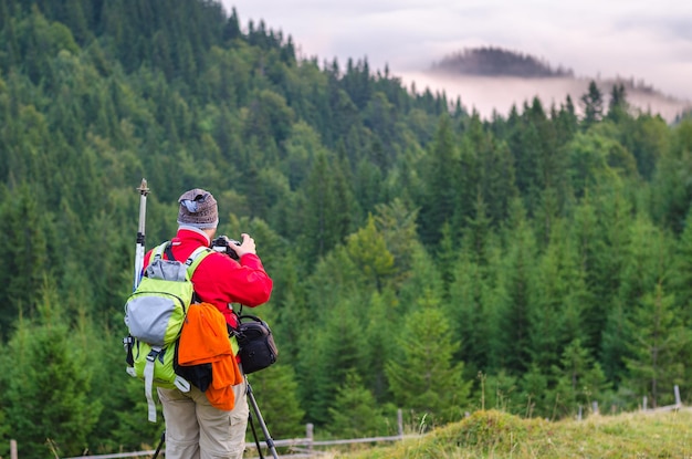 Photographer or traveler takes photos with digital camera in carpathian forest