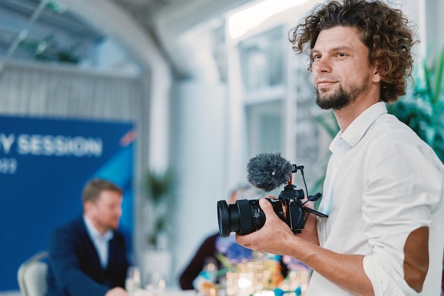 Photo photographer with a digital camera in his hands stands in a restaurant and looks away