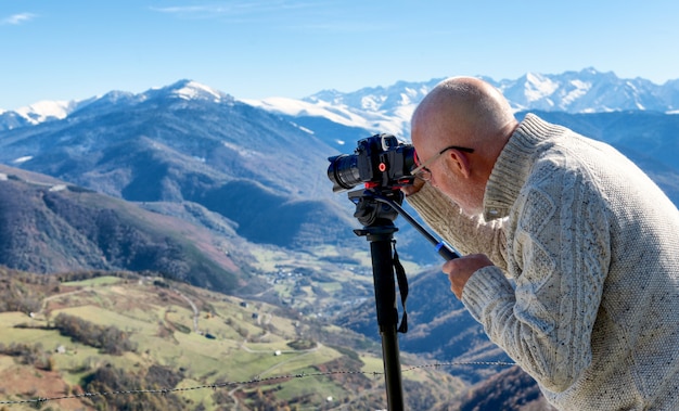 Fotografo con fotocamera digitale in cima alla montagna