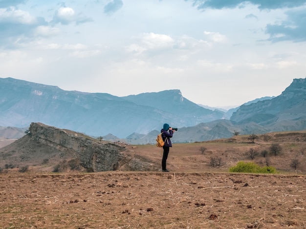 A photographer with a large camera takes pictures of a beautiful mountain landscape.