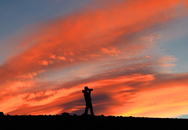 Fotografo con macchina fotografica di fronte al cielo rosso