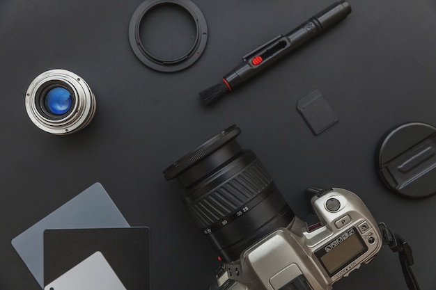 Photographer workplace with dslr camera system and camera accessory on black background