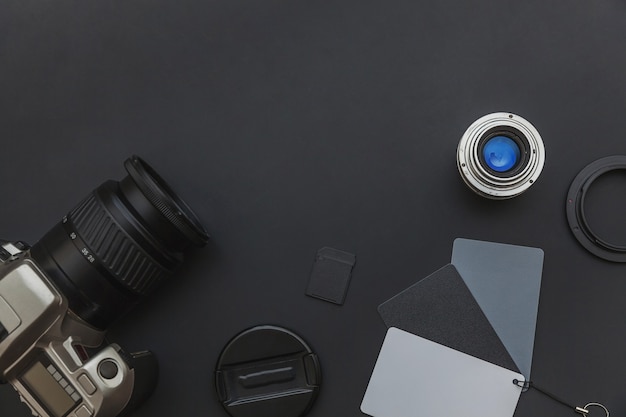 Photographer workplace with dslr camera system, camera cleaning kit, lens and camera accessory on dark black table background. Hobby travel photography concept. Flat lay top view copy space