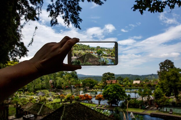 손에 스마트폰으로 사진 촬영 여행 컨셉 발리 티르타 강가의 워터 팰리스