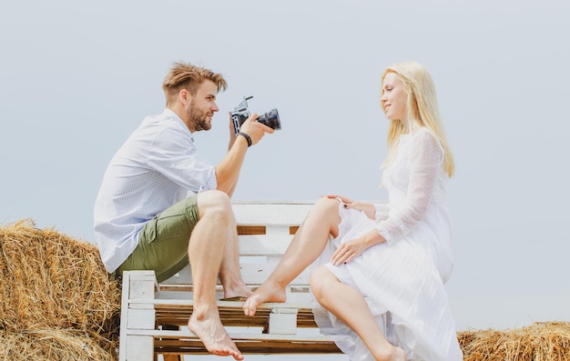 Photographing Women posing for handsome man Photographer with camera on sunny day Friends photographing on blue sky