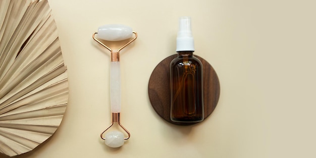 Photography from above of facial rolleroil dropper and palm leafEco friendly cosmetics mockup