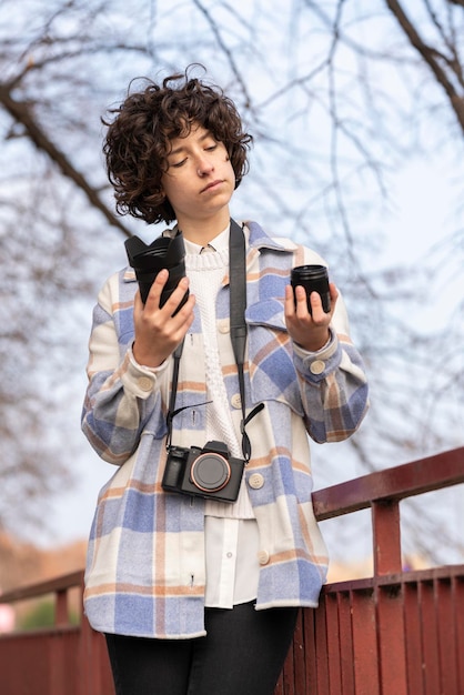 Photography student young brunette woman with curly hair choosing a lens for her camera on the street