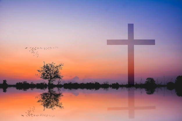 photomontage of cross against silhouette of mountain and lake view at sunset