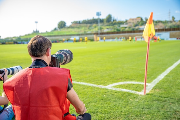 サッカーの試合で望遠レンズを持つフォトレポーター