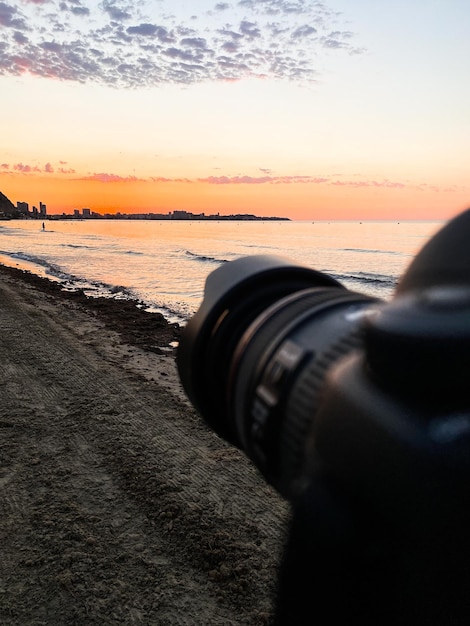 Photos of a camera on a tripod taking pictures at sunrise on the beach, because it is the photograph