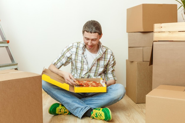Photos of men eating pizza among cardboard boxes