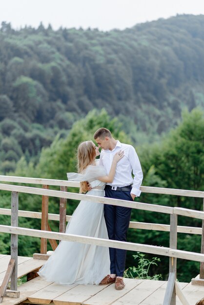 Servizio fotografico di una coppia innamorata in montagna. la ragazza è vestita come una sposa con un abito da sposa.