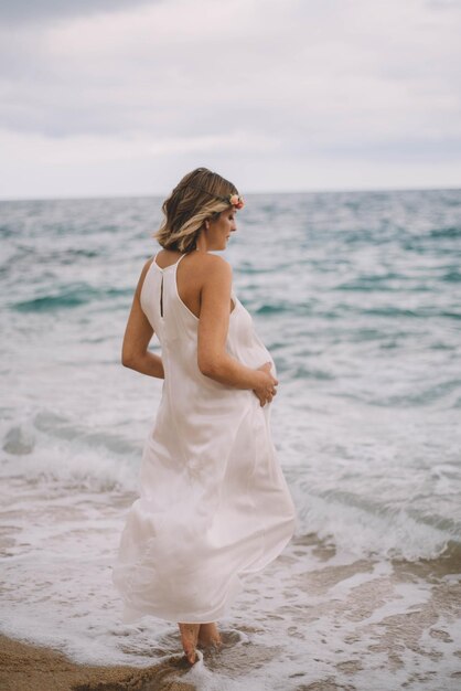 Servizio fotografico di una donna incinta che cammina sulla spiaggia