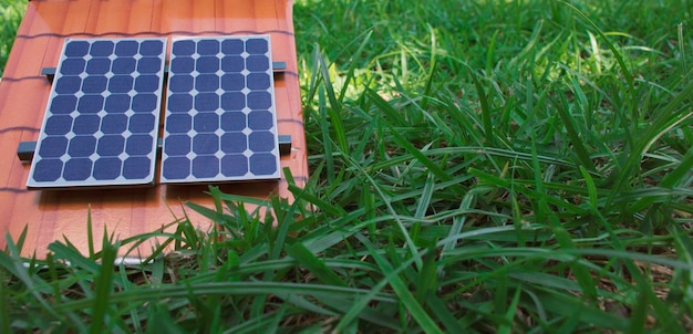 Photovoltaic solar panel next to a plug wire on grass background Alternative clean and renewable energy concept