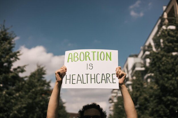 The phrase abortion is healthcare drawn on a carton banner in\
hand