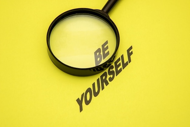 Phrase be yourself on a yellow background the word be magnified with a magnifying glass