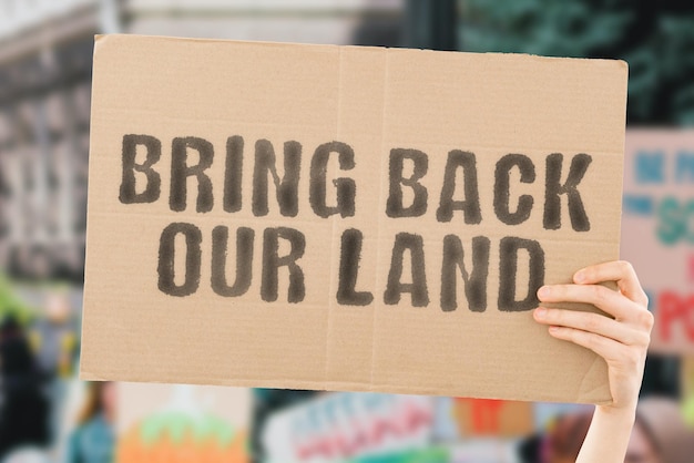 The phrase Bring back our land on a banner in mens hand Plot House Agriculture Protest