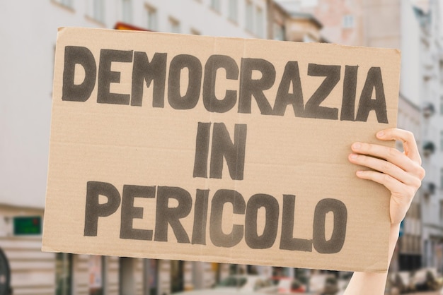 The phrase Democracy in danger is on a banner in men's hands with blurred background Politics Problem Solution Protest Political crisis Collapse Crush