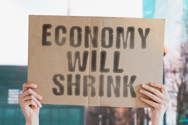 The phrase Economy will shrink on a banner in mens hand Business Financial crisis Collapse