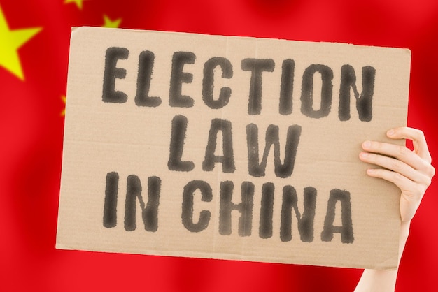 The phrase Election law in China on a banner in mens hand with Chinese Constitution Political