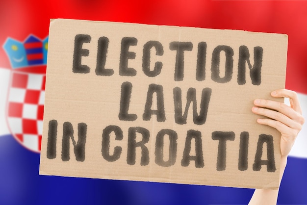 The phrase Election law in Croatia on a banner in men's hands with a blurred Croatian flag in the background Constitution Political Senate Zagreb Electorate Majority