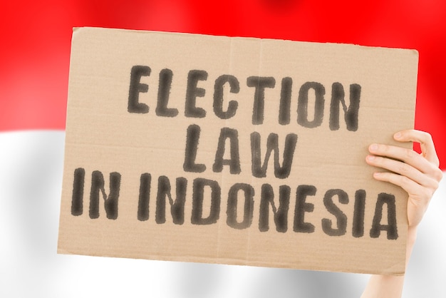 The phrase Election law in Indonesia on a banner in mens hand with Indonesian flag Constitution