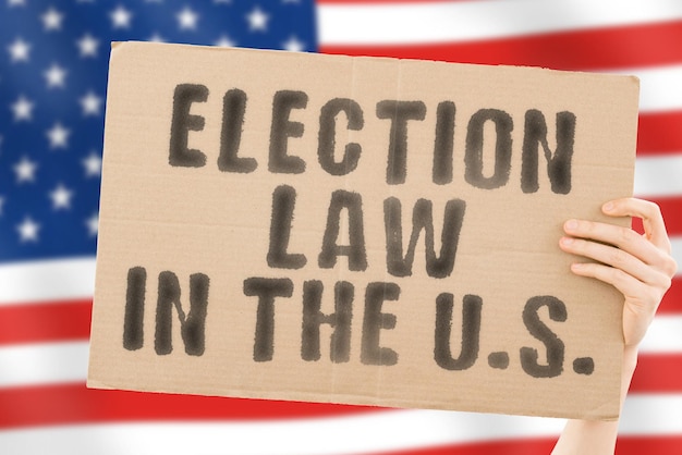 The phrase Election law in the US on a banner in mens hand with American flag Constitution