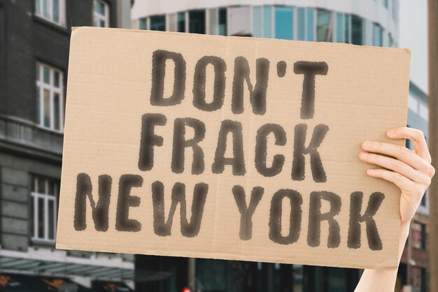 The phrase don\'t frack new york on a banner in men\'s hands with\
blurred background territory control harm system source supply\
wealth vitality air toxin bad resources energy health