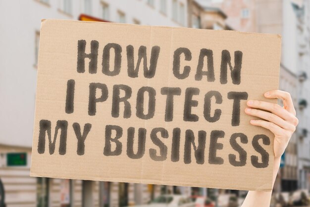 The phrase How can I protect my business is on a banner in men's hands with blurred background Personal Plan Service System Teamwork Defense Web Work Datum Paper Insurance Internet