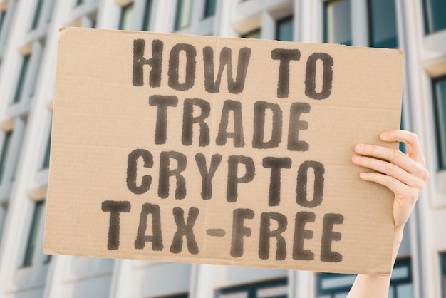 The phrase how to trade crypto taxfree is on a banner in men's hands with blurred background online invoice risk stock rate duty dollar fund growth internet law legal network