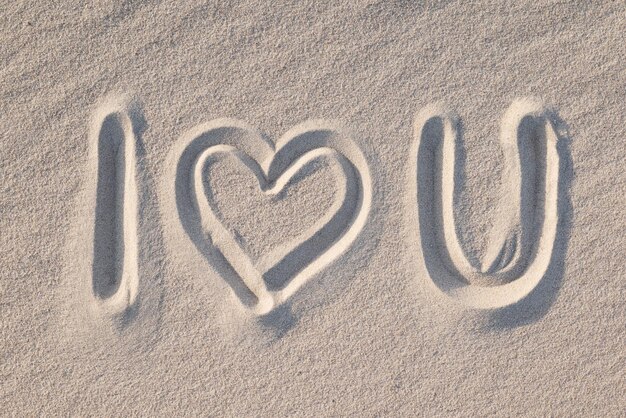 Phrase I love you drawn on the sand instead of word love shape of a heart close up