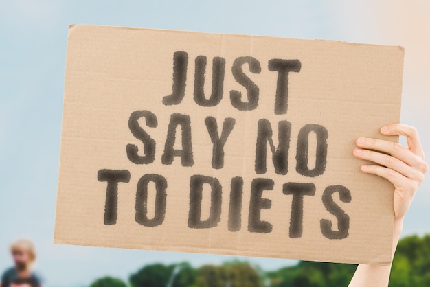 The phrase Just say no to diets on a banner in mens hand Nutrition Eating Healthcare Diet