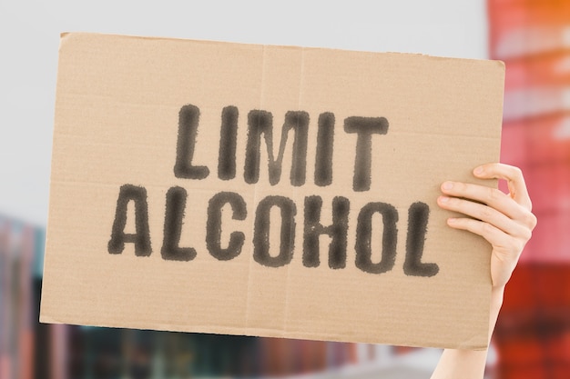 The phrase  Limit Alcohol  on a banner in mens hand Drink Addiction Drunk Risk Dangerous