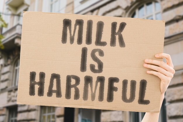 The phrase  Milk is harmful  on a banner in mens hand with blurred background Negative Toxic