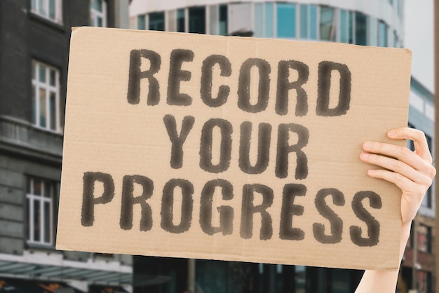 The phrase Record your progress on a banner in mens hand Rise Increase Improve Evolution