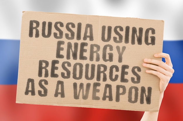 The phrase Russia using energy resources as a weapon on a banner in mens hand Gas Aggression