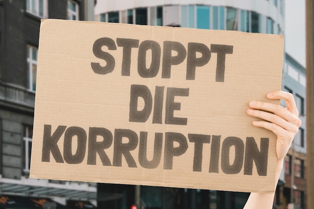 Photo the phrase stop corruption on a carton banner in men's hand human holds a cardboard with an inscription protest power government criminal