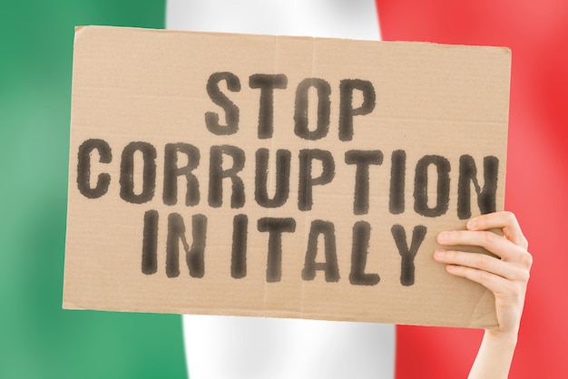 背景にぼやけたイタリアの旗を持つ男性の手のバナーにイタリアで腐敗を止めるというフレーズ禁止されている富の犯罪を防ぐ腐敗経済腐敗しやすい政治