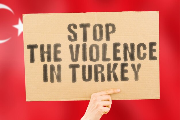 The phrase stop the violence in turkey is on a banner in men\'s\
hands with a blurred turkish flag in the background sad rights\
security social stress combat hate cruelty furious