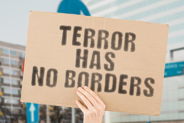 The phrase terror has no borders is on a banner in men\'s hands\
with blurred background terrorist army assault frighten head male\
anger afraid dangerous crime offense evil violation