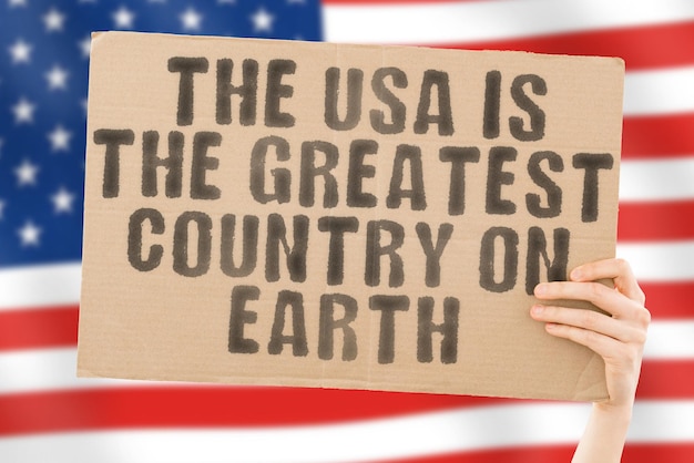 The phrase The USA is the greatest country on earth is on a banner in men's hands with blurred background Positive Independent Constitution Strength Revival Support Team Strong Success