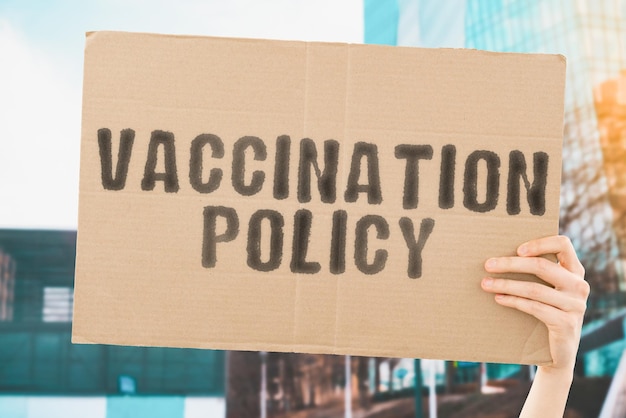 The phrase Vaccination policy on a banner in men's hand with blurred background Cure Heal Remedy Medicine Pandemic Rules Healthcare Solution Healthcare