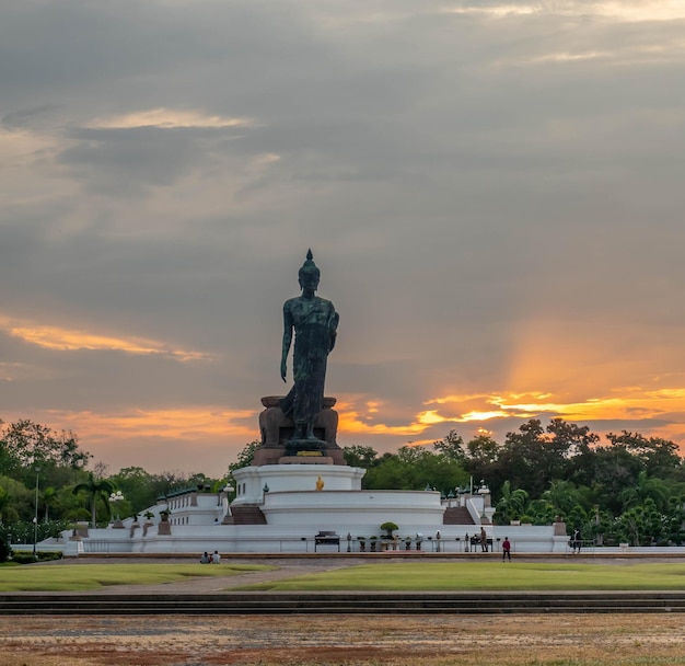 Phutthamonthon Buddha walking statue under evening cloudy sky in Thailand