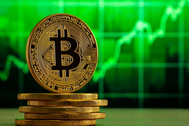 Bitcoin fisico in piedi su un tavolo di legno davanti a un grafico verde